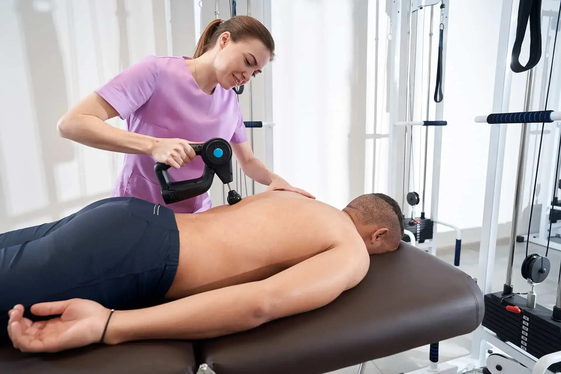 A therapist using a massage device on a patient's back